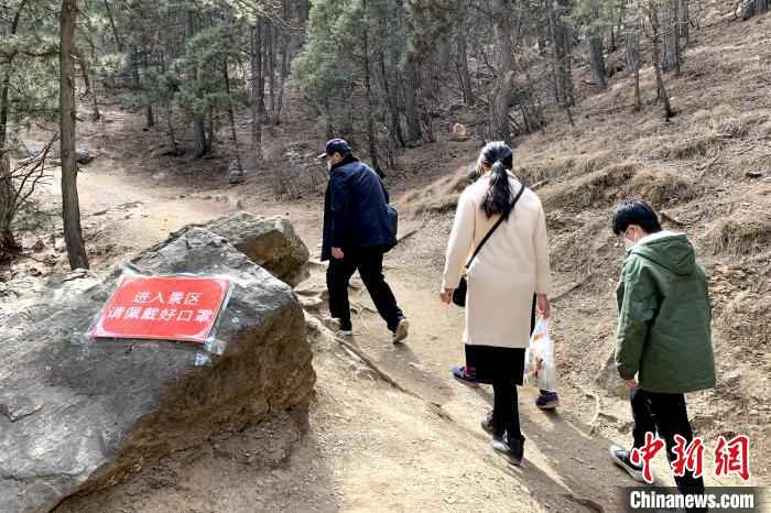 景区内张贴了许多防疫宣传标语,游客带着口罩游玩。 李佩珊 摄 贺兰山间春风起 游客理性踏青游